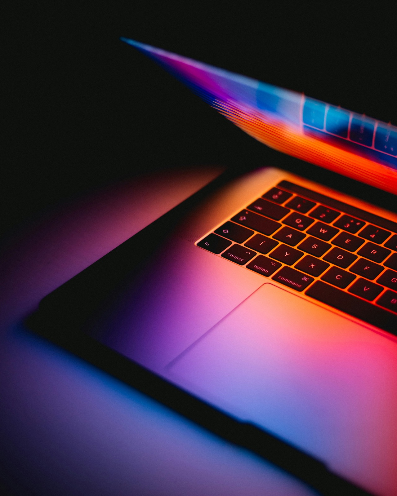 Laptop bathed in purple, pink, and orange light
